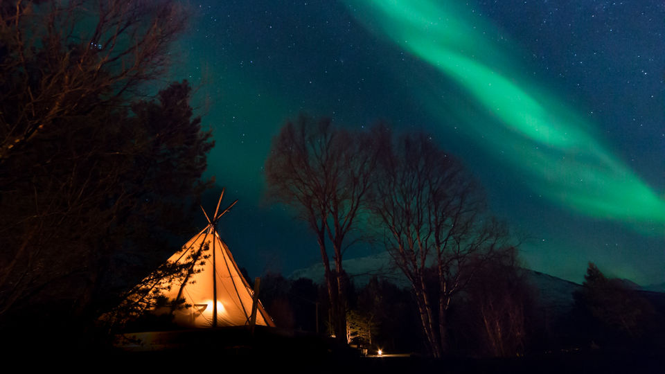 aurora boreal display under a tipi in norway