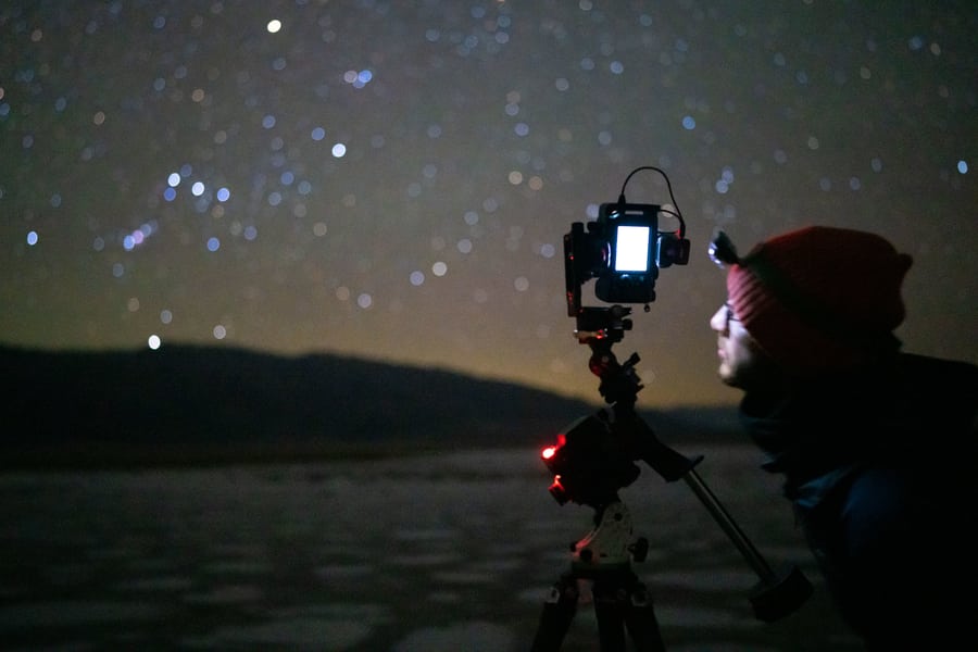 Fotógrafo mirando a la pantalla LCD de su cámara durante una sesión de fotografía nocturna