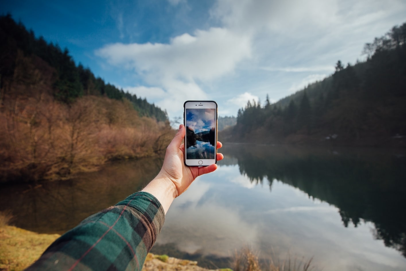 Person using phone in the mountains, how to plan a vacation