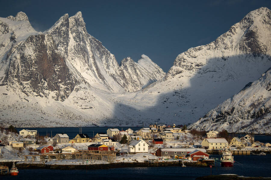 Snow covered peaks stand tall behing Reine in Lofoten, Noway