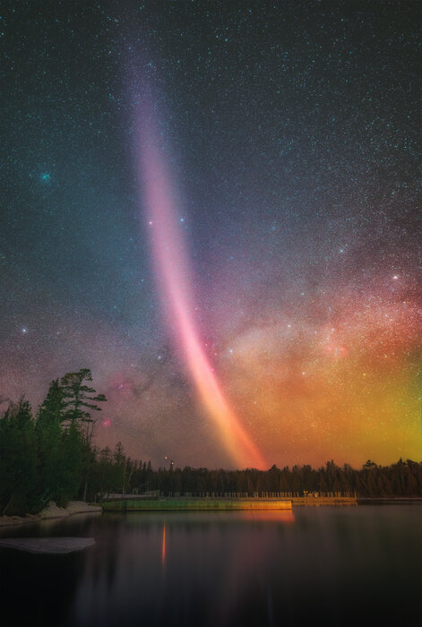 Strong northern lights seen over a lake in Keweenaw Peninsula with the Milky Way behind it