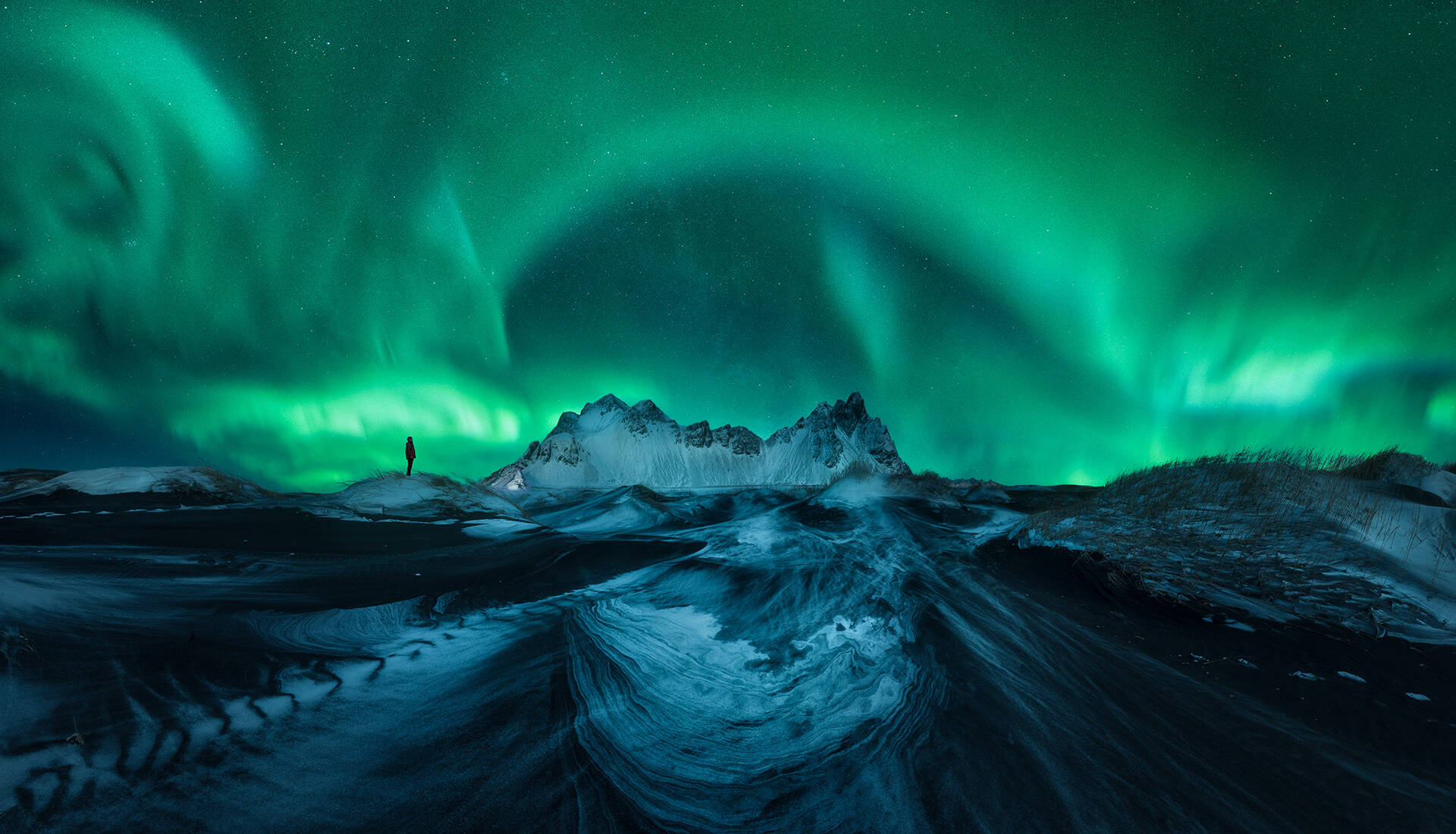 Panorámica de una Aurora Boreal que cubre el cielo nocturno sobre Vestrahorn en Islandia
