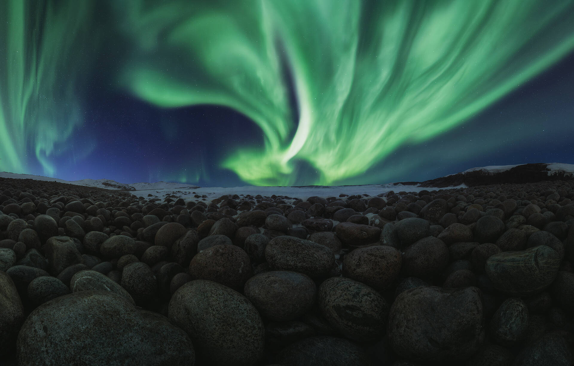 Una Aurora Boreal cubre el cielo nocturno sobre unas rocas