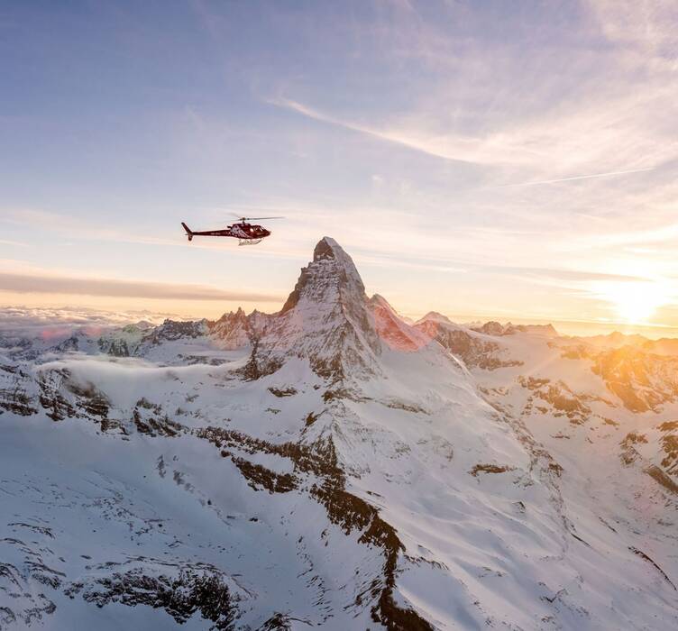 Helicopter flying next to the snow-covered Matterhorn during a cold season