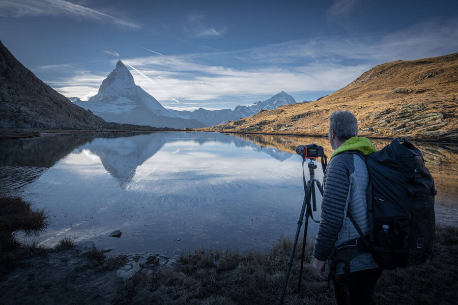 Photographer taking a photo of the Matterhorn with a reflection on the lake