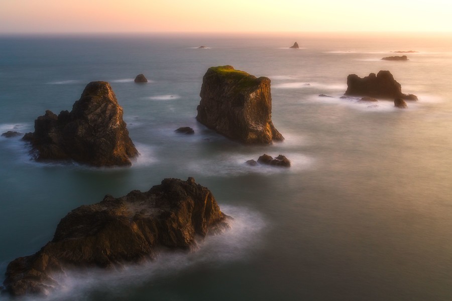 Golden sunset light shines over sea stacks on the Oregon Coast