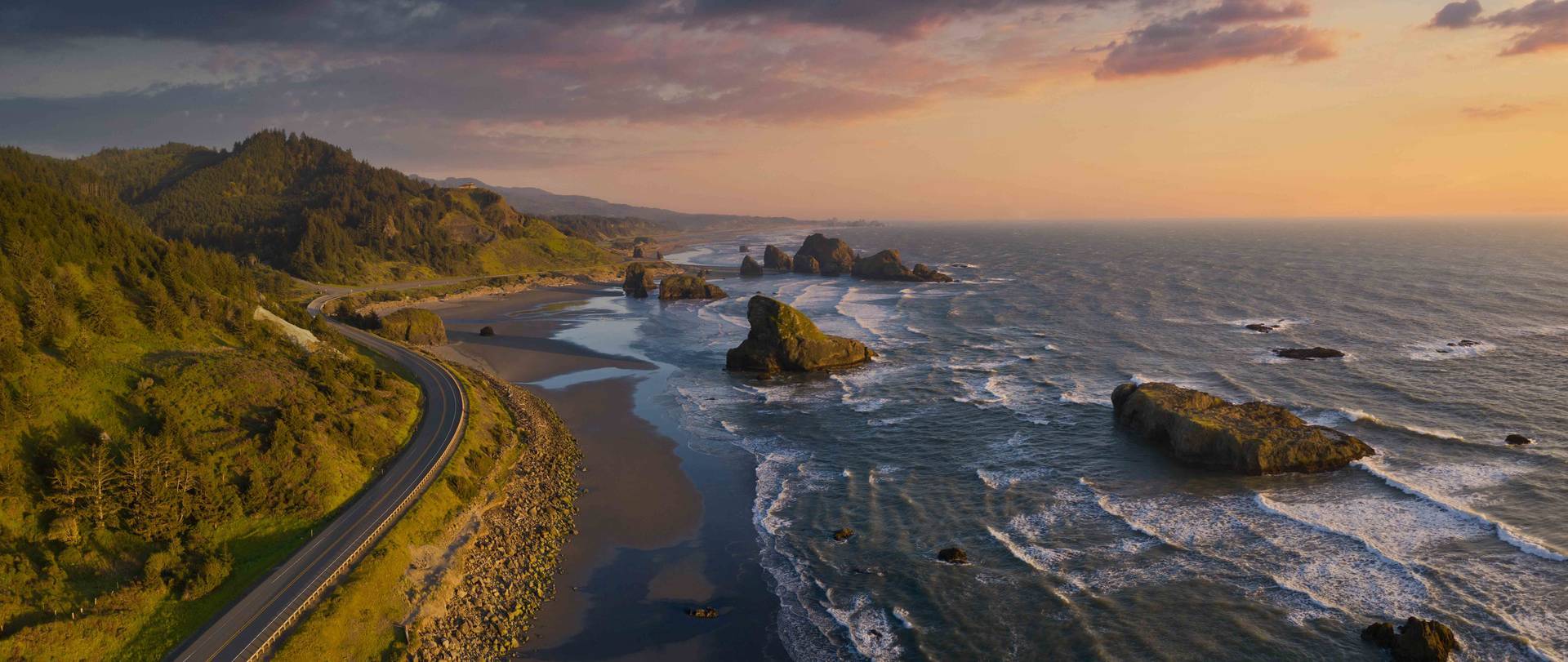 Aerial view of the coast of Oregon highlighting a road and the sea stacks during sunset
