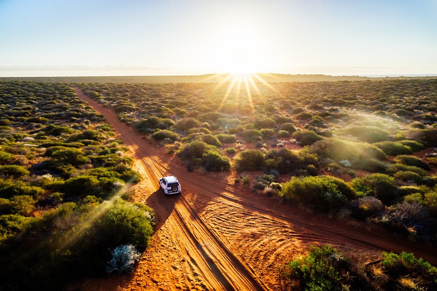 All wheel drive type of car cruising into the horizon in a bright sunset in the Australian Outback