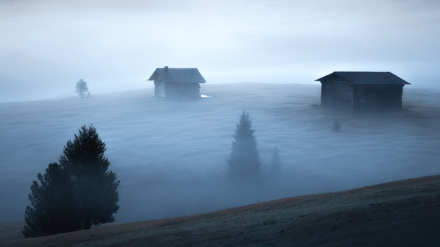 Cabins in Alpe di Siusi covered in thick morning fog