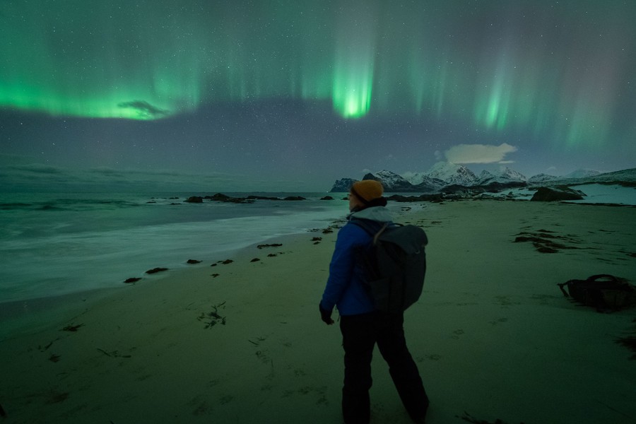 Photographer posing under a bright green aurora