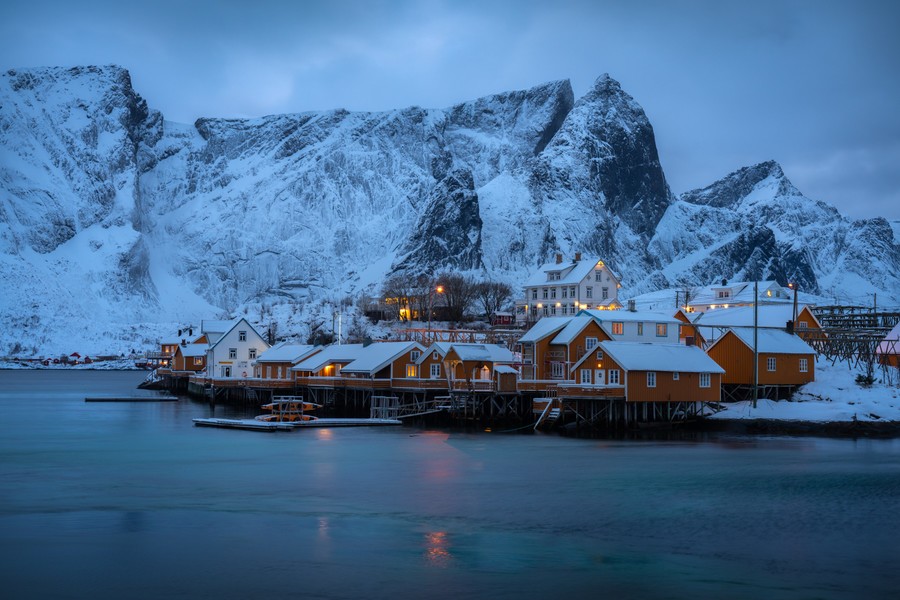 Yellow cabins in Lofoten Islands with a snowy mountain in the background