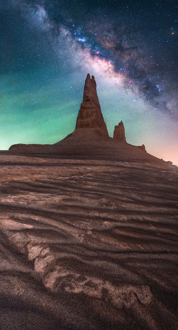Bright Milky Way covering the sky over a rock formation in the desert