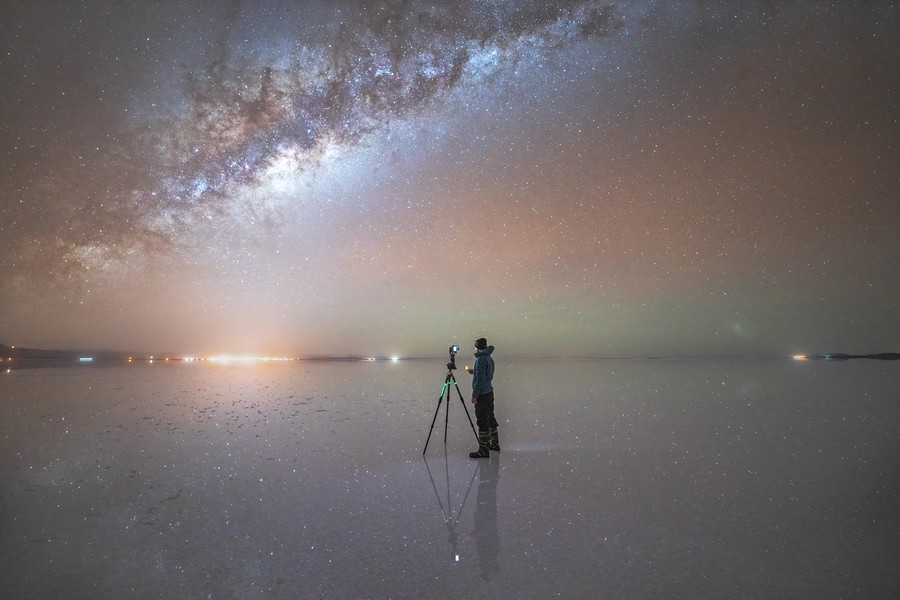 Person standing in the middle of salar de uyuni under the night sky with the milky way