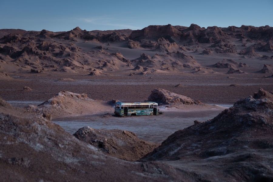Abandoned bus in the desert surrounded by rock and sand formations