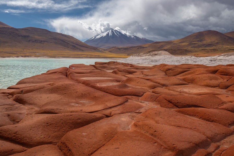 Reddish rock formations with a snow-capped mountain in the background