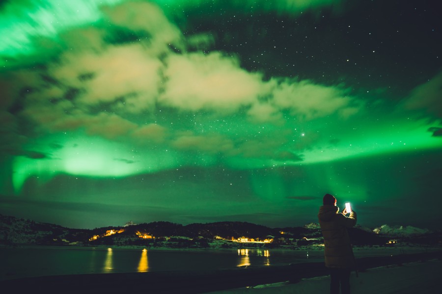person photographing the northern lights with a smartphone
