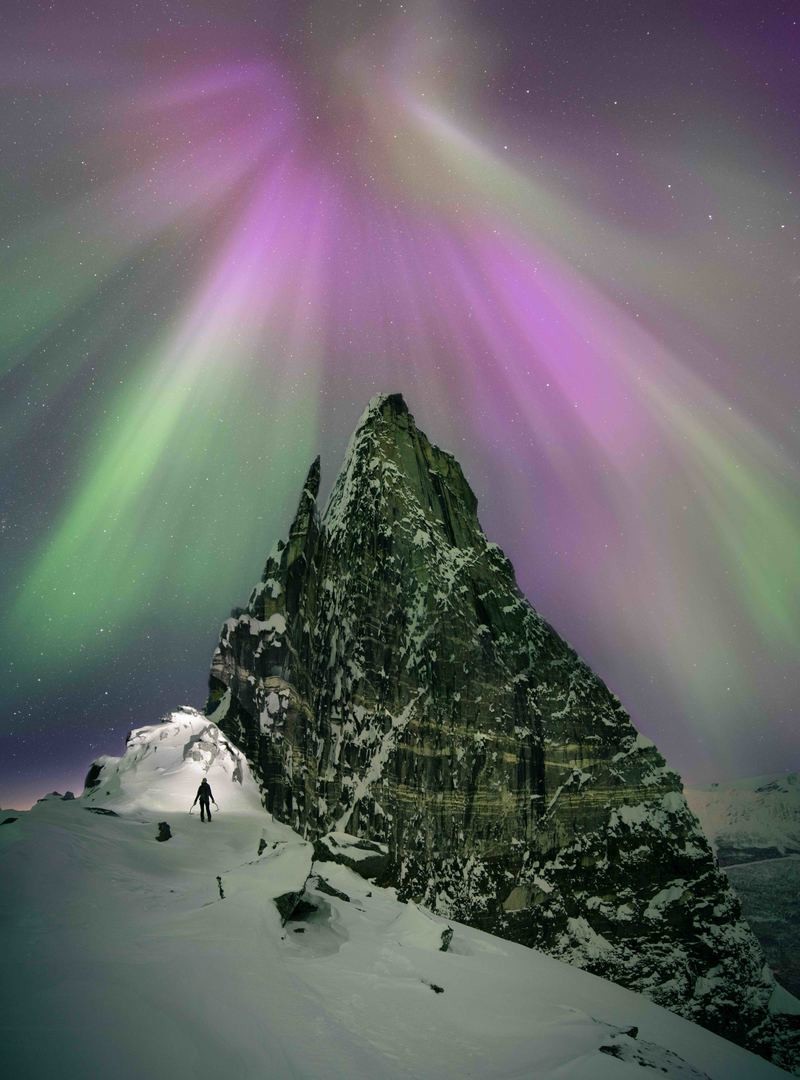 Aurora brilla fuertemente sobre un pico de montaña