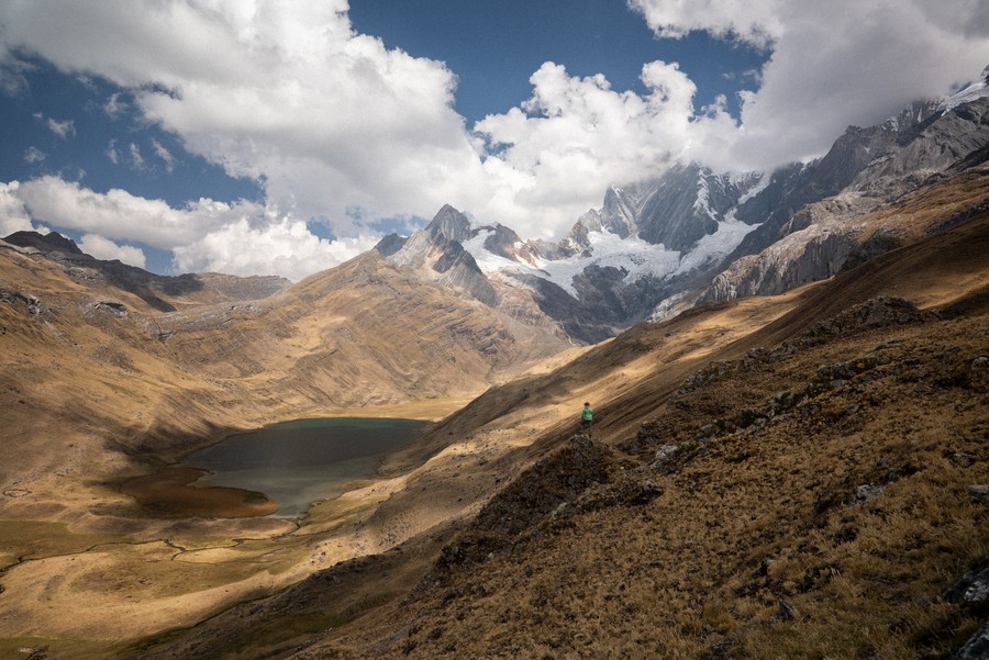 Persona de pie en una colina con montañas al fondo