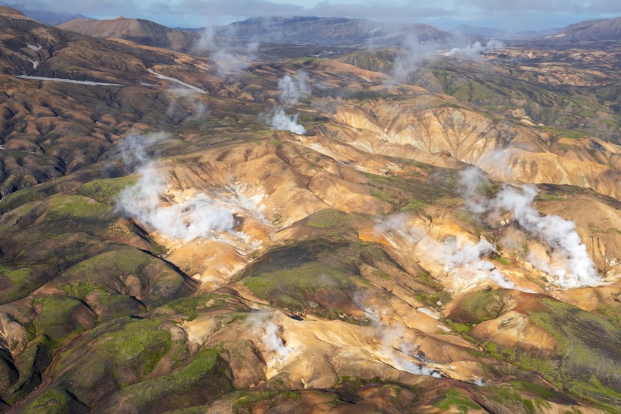 Terreno montañoso y accidentado en las Tierras Altas de Islandia con chimeneas de azufre humeantes