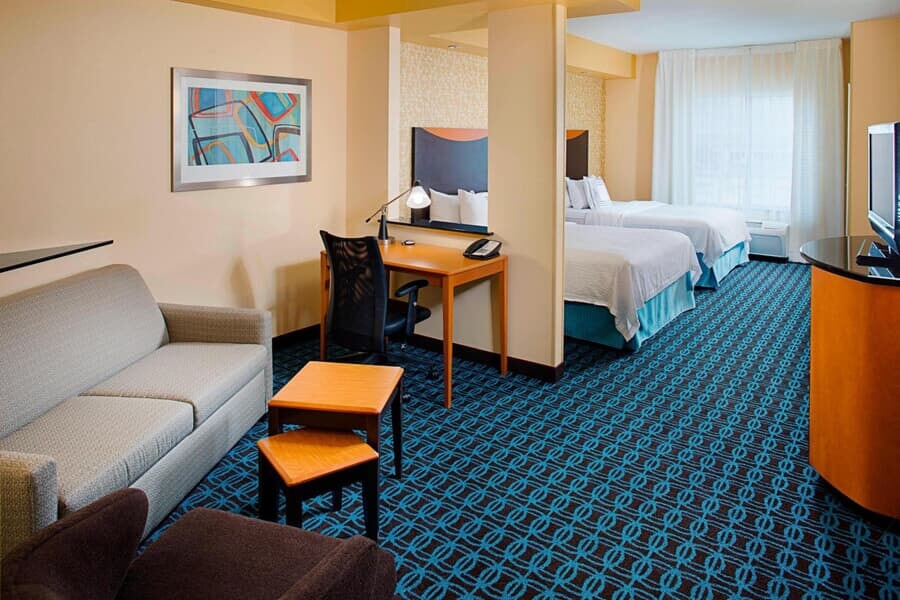 Hotel room view, two beds, blue carpet floor and couch