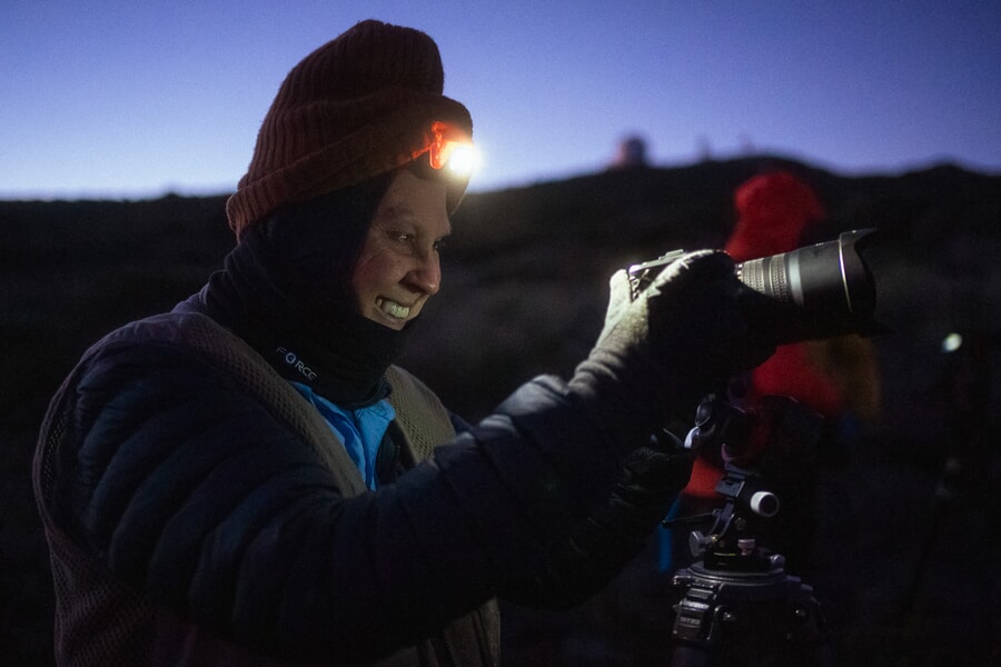 Smiling woman with a headlight taking pictures at night